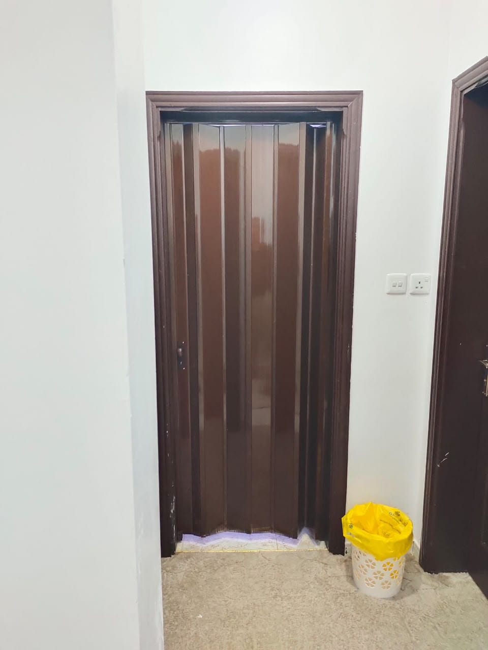 باب سحب كورديون بني مغلق بإطار خشبي داكن